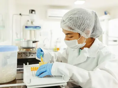 Profesional de laboratorio con cofia y guantes trabajando en la mesada
